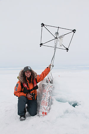 A traveler at the North Pole kneels beside a sea ice instrument