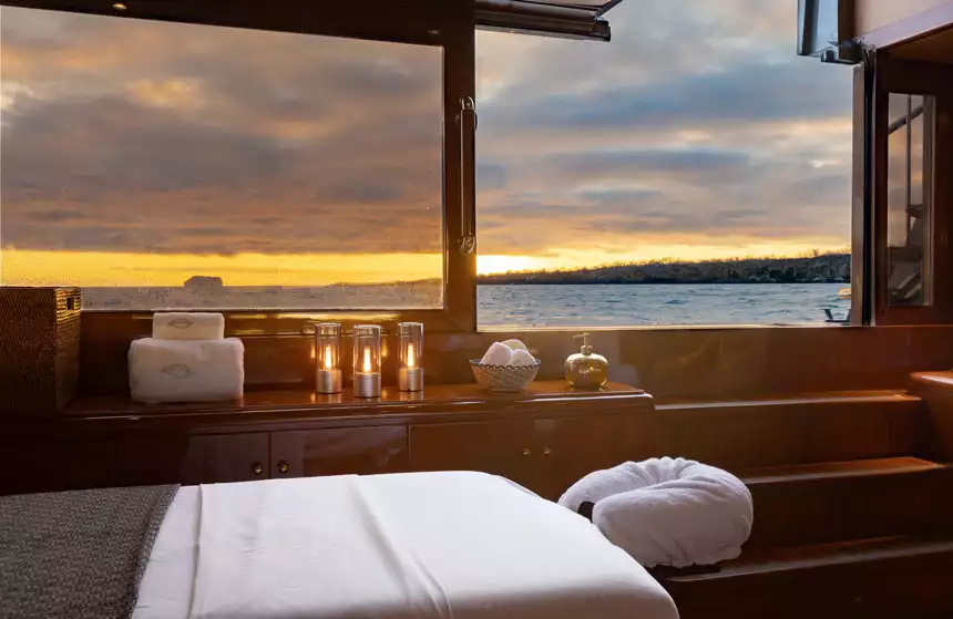 Massage table with candles & towels aboard a romantic cruise ship, steps from the aft swim step at sunset in Galapagos.