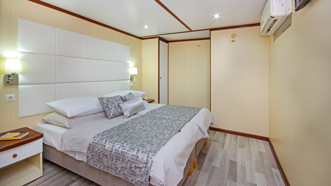 The Aurora yacht's main deck premium cabin showing a double bed with cream colored walls