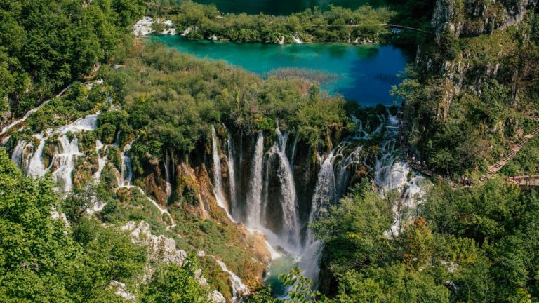 Cascading waterfalls among the trees at Plitvice Lakes seen from above with a footpath barely visible to the right
