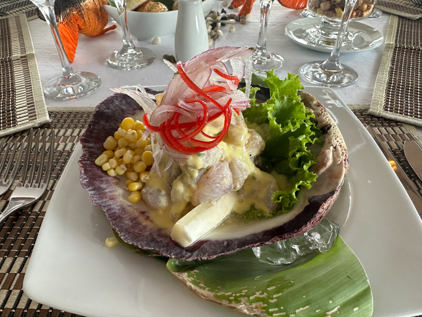A brightly colored salad with yellow corn, green lettuce, purple onion, and other vegetables are served on white plate. 
