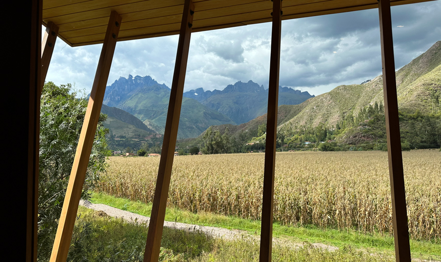 In Peru, the view from Explora Sacred Valley Lodge, jagged green mountains, and yellow corn fields.