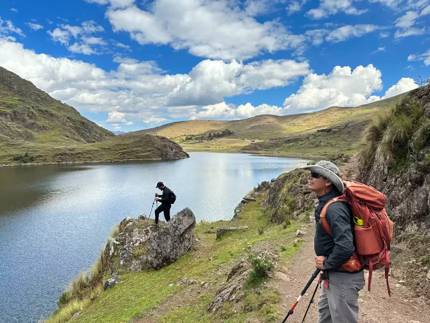 Exploring the Sacred Valley of Peru with guide and other guests. Blue sky day, green lush mountains and a high alpine lake.