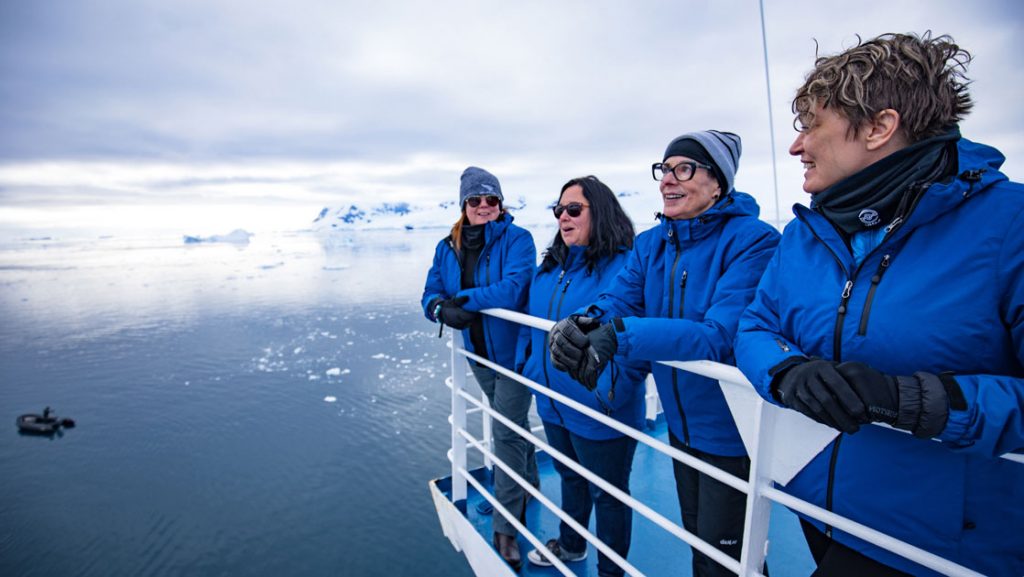 4 women stand on upper deck of expedition ship on cloudy day of an Intrepid Antarctica Journey to the Antarctic Circle voyage.
