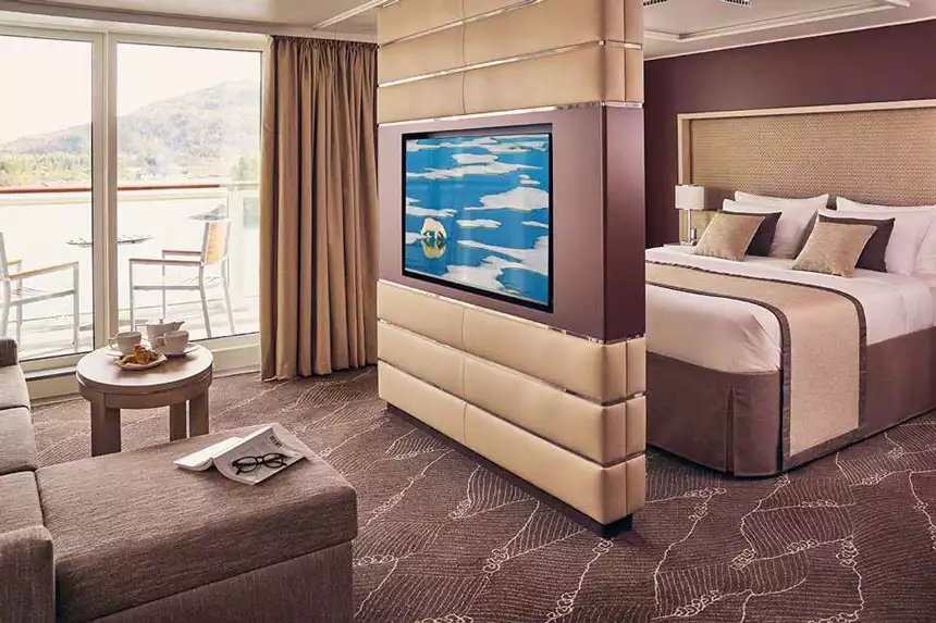 Antarctica ship cabin rendering showing sliding glass doors to private balcony, seating room, bedroom and floating TV wall.