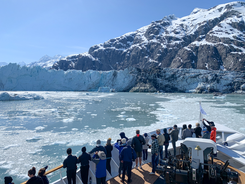Safari Endeavor passengers gather on the bow to take in the views of a sweeping glacier in front of them.