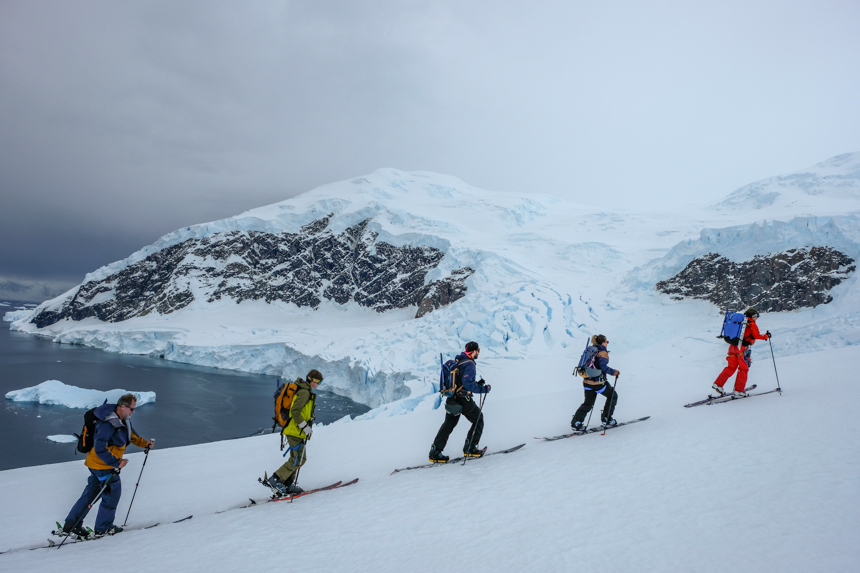 Skiers enjoy snowy cold pristine white conditions in Antarctica as they tour uphill with skis on their feet in october. 
