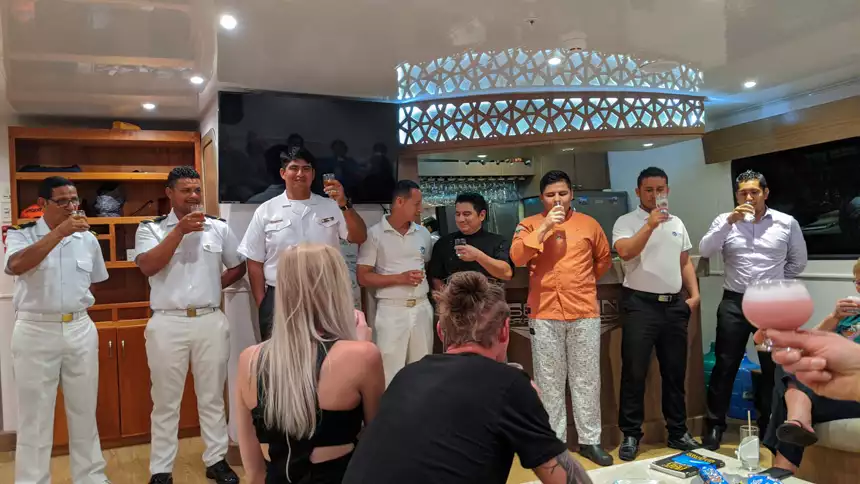 Staff and crew aboard Seaman Journey stand in front of guests and raise their glasses for a toast. 
