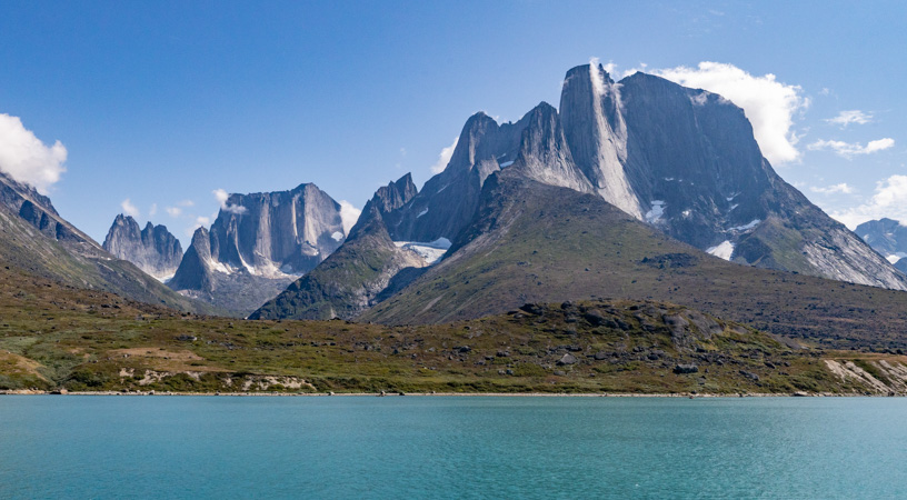 In South Greenland tall jagged granite peaks and turquoise water are set against blue sky