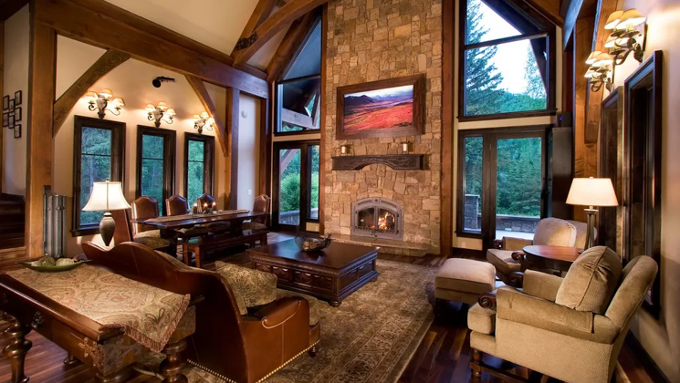 Living room of 1 of the Homes at Kenai Riverside Lodge with high ceiling, large windows, gas fireplace & oversize furniture.