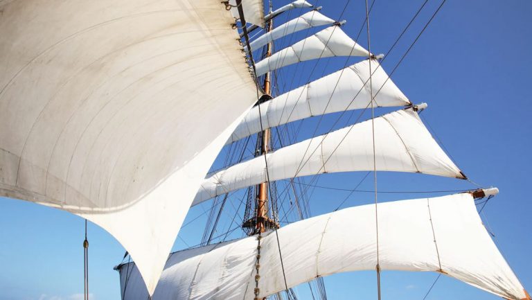 6 white sails from mast of tall ship billow in the wind on a sunny, blue-sky day of an Italian Riviera cruise on Sea Cloud II.