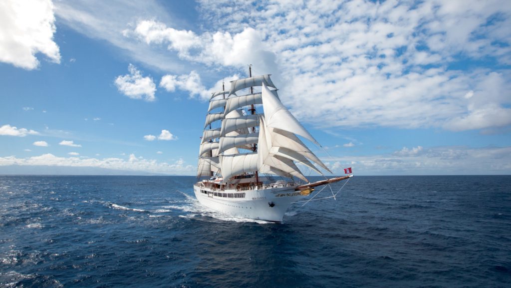 Sea Cloud II: Lindblad 3-masted barque tall ship with white exterior sails in open waters on a partly cloudy day.