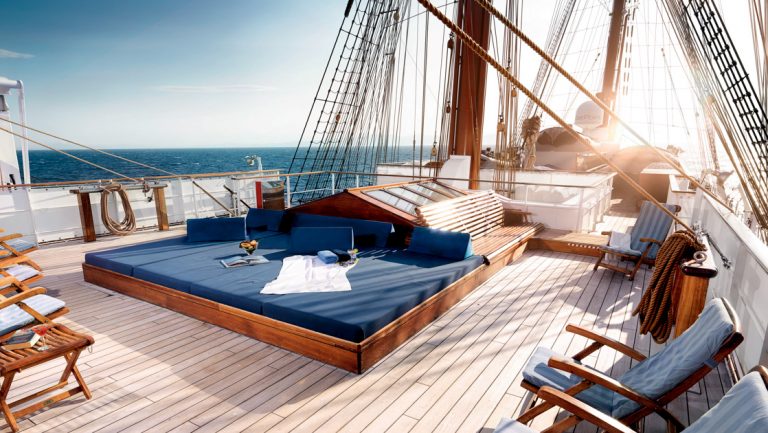 Sea Cloud II: Lindblad 3-masted motorsailor's Sun Deck with teak decking & dark blue padded sun loungers & chairs.