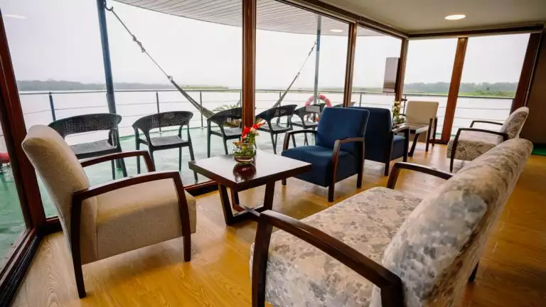 lounge area for guests a aboard small cruise ship with couches and large windows to relax and enjoy the river