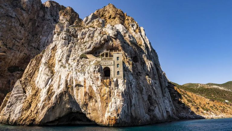 Sardinia castle built into a cliff overlooking calm sea, seen on a cruise from Athens, Greece to Barcelona, Spain.