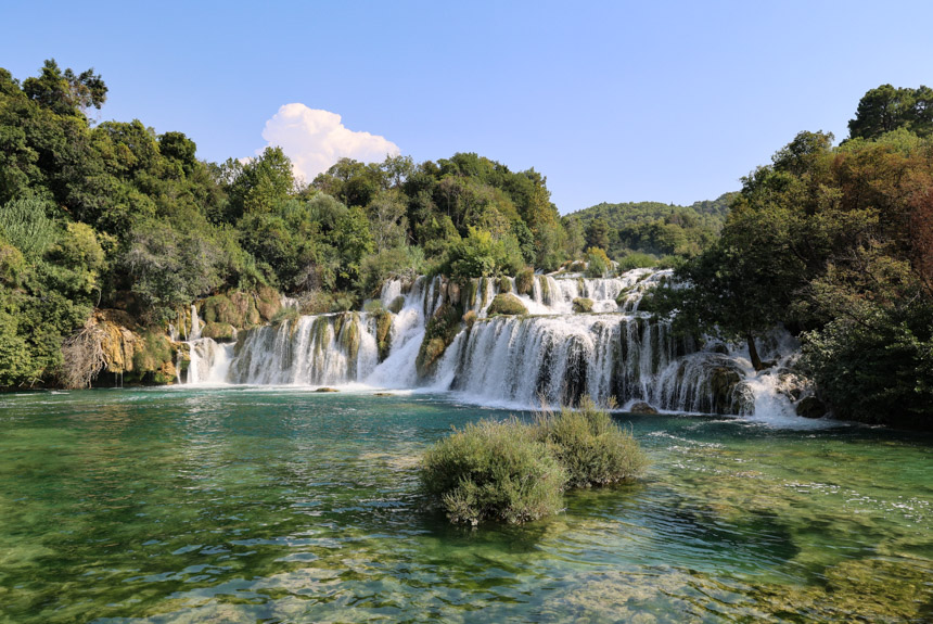 Krka National Park waterfalls seen cascading on a blue-sky day with clear water