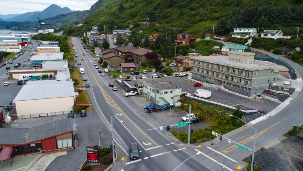 Aerial view of Kodiak Compass Suites hotel in Alaska on a cloudy day, 1 block off the water & backed by tall green mountains.