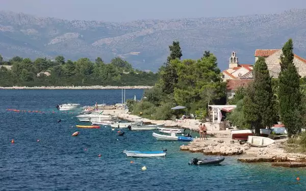 A view of a shoreline in Croatia with vacationers and boats on the rocky shoreline