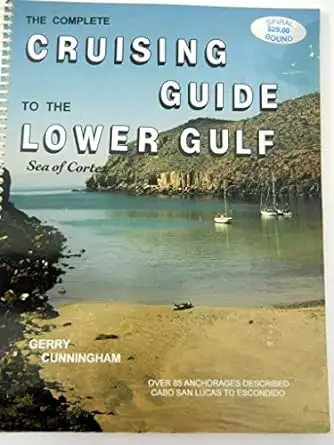 Book cover of the Cruising Guide to the Lower Gulf, Sea of Cortez showing a photograph of a tan beach with two sailboats in a calm cover surrounded by rocky desert landscape and blue sky.  