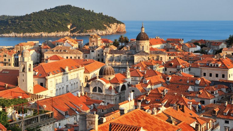 Aerial view of Dubrovnik, Croatia with its red-tiled roofs, stone buildinga, domes & seaside setting on a sunny day.