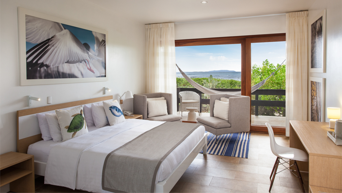 King bed, writing desk, comfortable chairs and hammock with ocean view in suite at Finch Bay Eco Hotel in the Galapagos Islands