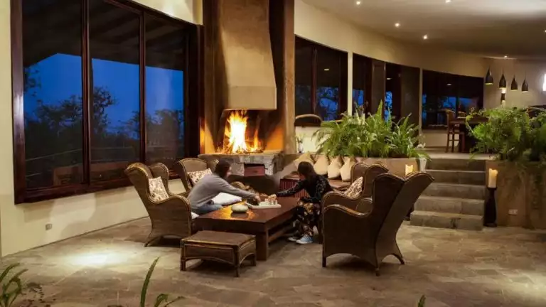 Lounge area with large fire place in lodge with 2 guests enjoying the sitting area.