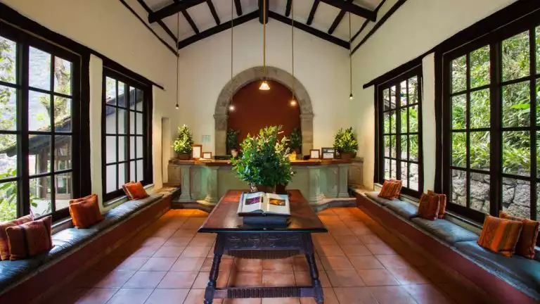 Front desk, for small machu picchu hotel with large windows on both sides , window benches, and greenery to set the mood