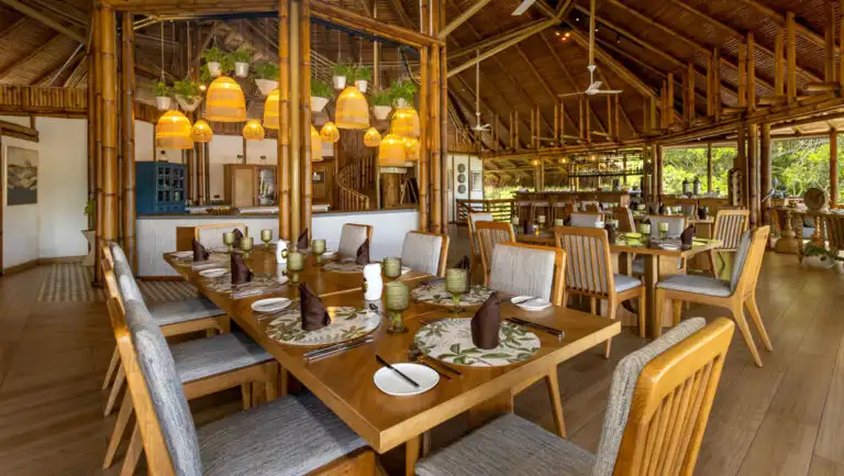 Inside the open-air dining room, with thatch-roof & wood tables at La Selva Amazon EcoLodge overlooking Lake Garzacocha.