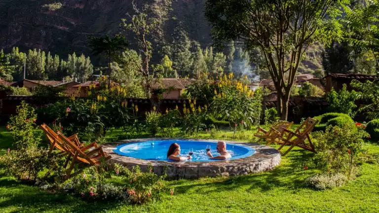 Couple enjoying a nice glass of wine in a blue hot tub surrounded by greenery