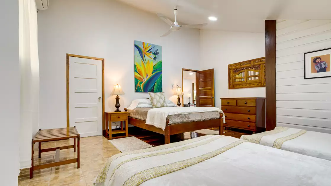 Bedroom in Wright House at the Lodge at Chaa Creek with 1 double & 2 twins in white bedding by wood furniture.