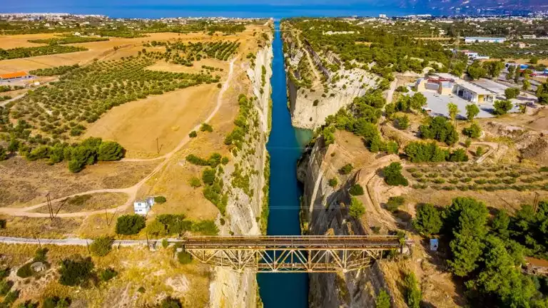 Ariel view of large canal in the Mediterranean with a dry desert climate, small green bushes and a bridge for citizens to cross