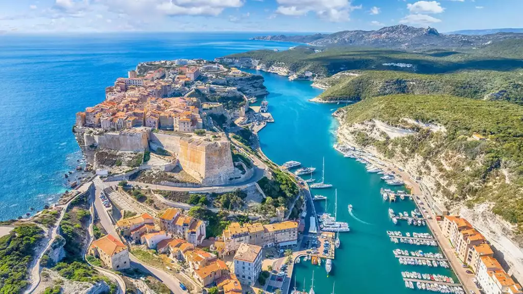 Ariel view of the breathtaking Bay of Corsica with small sail boats and ships parked next to ancient stone buildings and red toned roofs