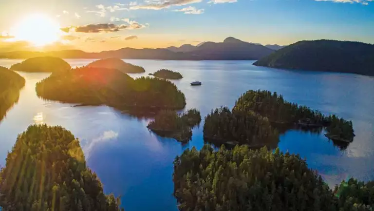 Aerial view of gumdrop green islands at sunset, seen on the Remarkable Journey to Alaska, British Columbia & Haida Gwaii cruise.