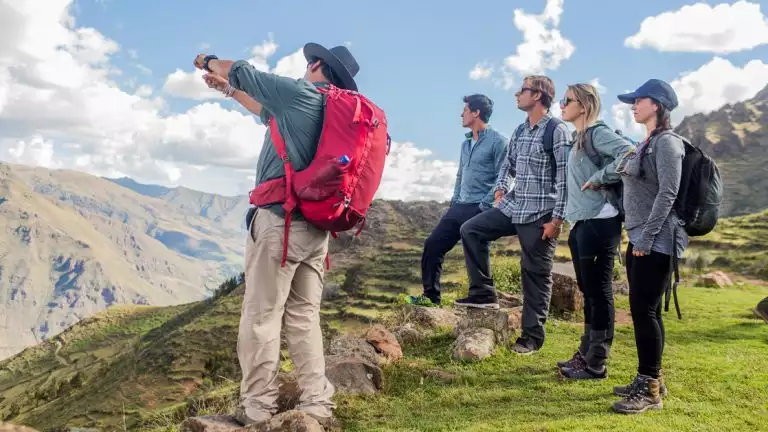 Hikers looking out into the views of machu picchu as the guide points out for all travelers