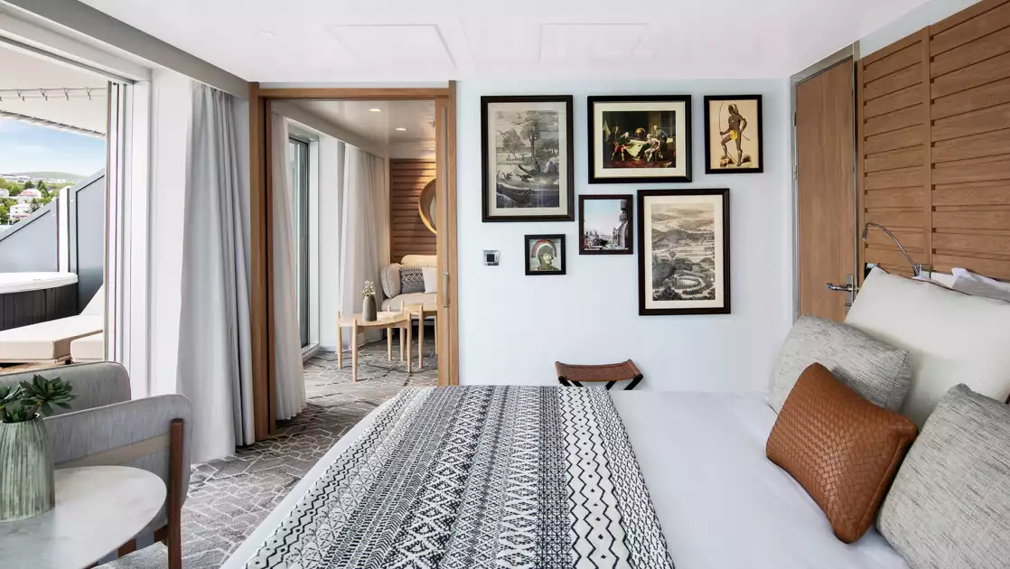 Owner's Suite on Le Laperouse expedition ship, with king bed, separate living room, bright white decor & framed wall art.