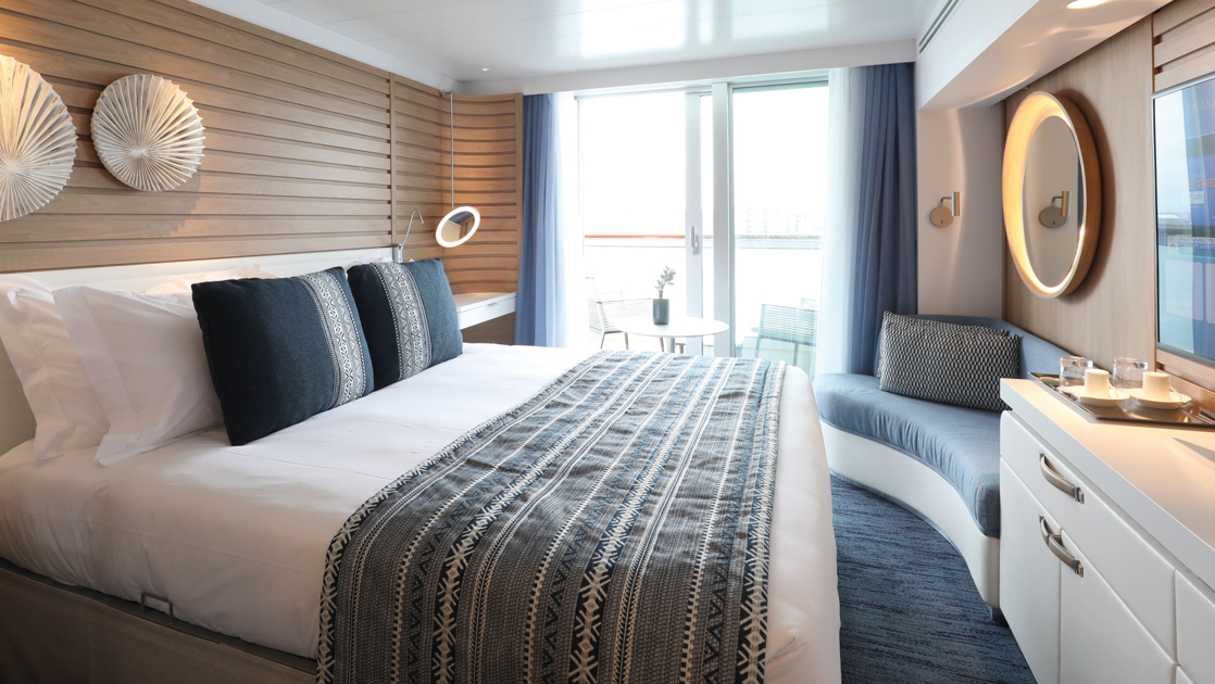 Prestige Stateroom on French expedition ship Le Laperouse, with king bed, white linens, chic ethnic decor & private balcony.