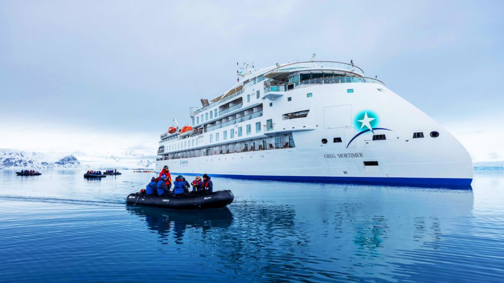 A small Zodiac cruising around small cruise ship in the arctic
