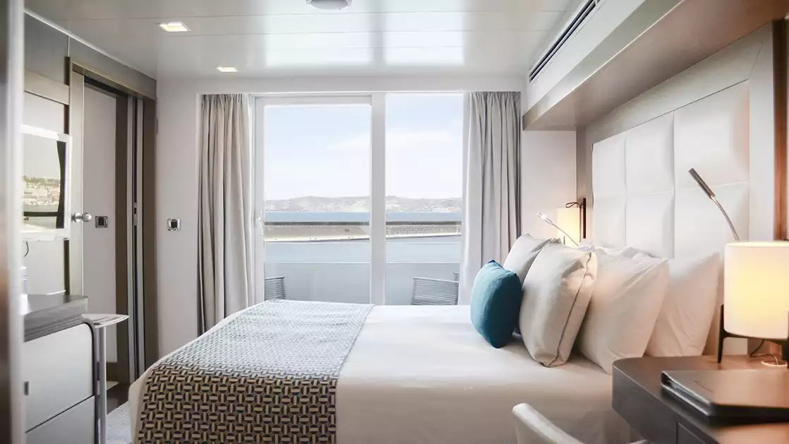 Prestige stateroom aboard L'Austral expedition ship, showing king bed, desk & white-&-copper appointments.