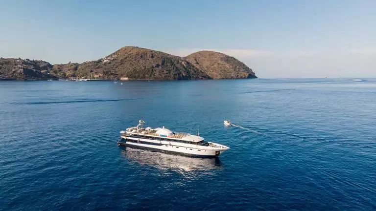 The yacht Harmony G seen from above at anchor among brown hills and blue ocean