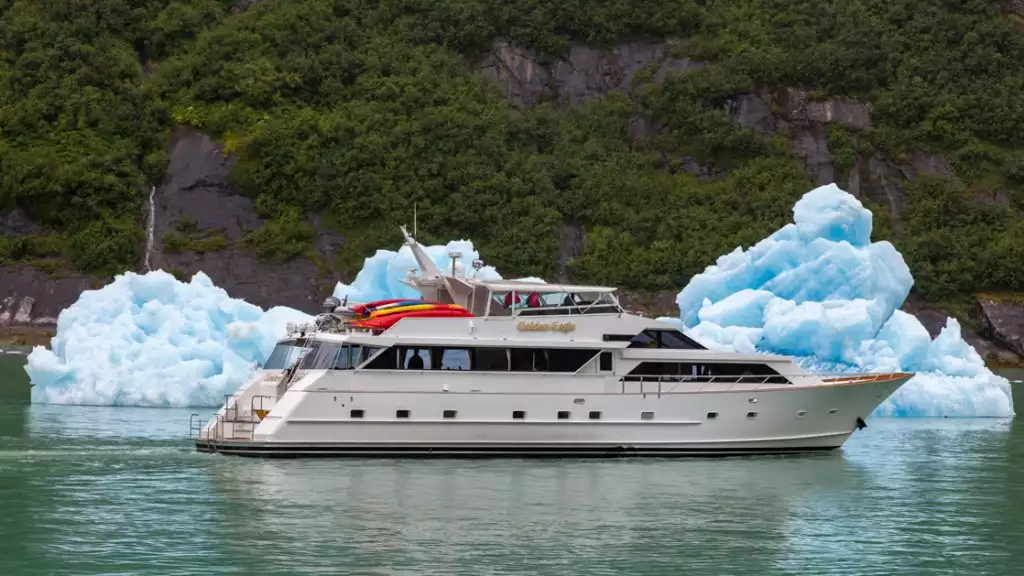 The Golden Eagle yacht small ship on a sunny day in Alaska floating infront of large icebergs