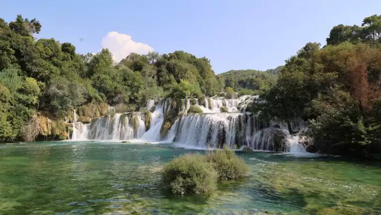 Wide waterfalls cascade into blue-green water among dense forest at Krka National Park, seen on a Lindblad Croatia cruise.