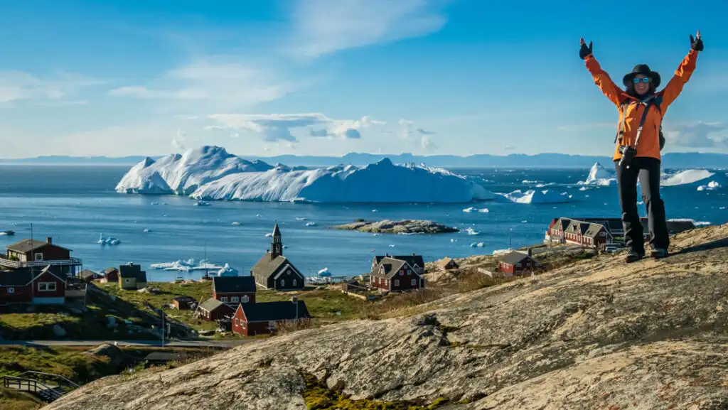 A guest poses at the scenic viewpoint above the historic Zion Church in Ilulissat, Greenland