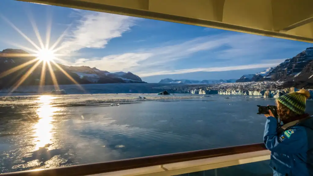 A guest takes photographs at Sunrise from the ship National Geographic Endurance, Northeast Greenland National Park, Greenland.