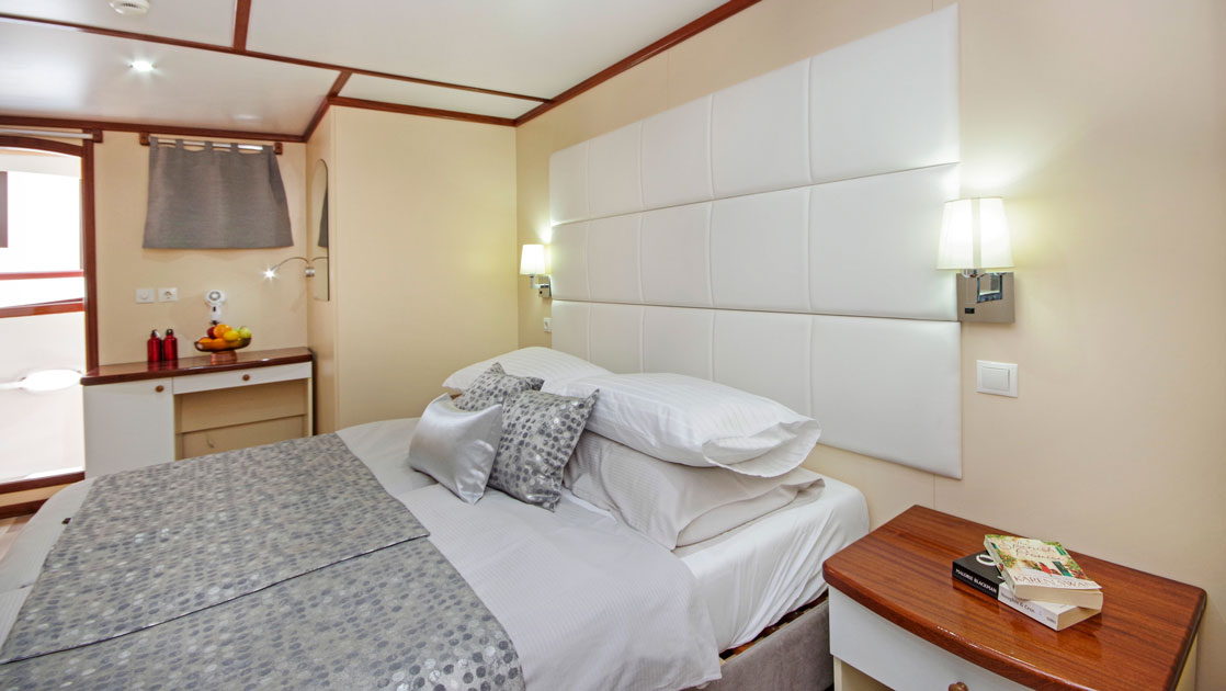 The Aurora yacht's main deck premium twin/double cabin showing a double bed with cream colored walls