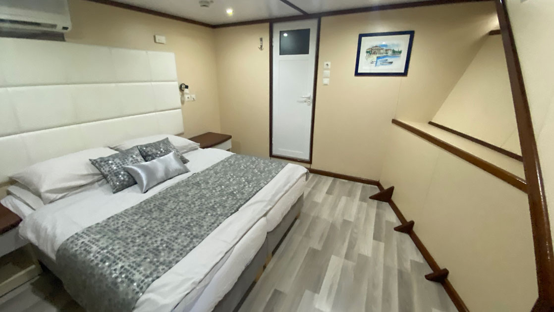 The Aurora yacht's main deck standard twin/double cabin showing a double bed with cream colored walls