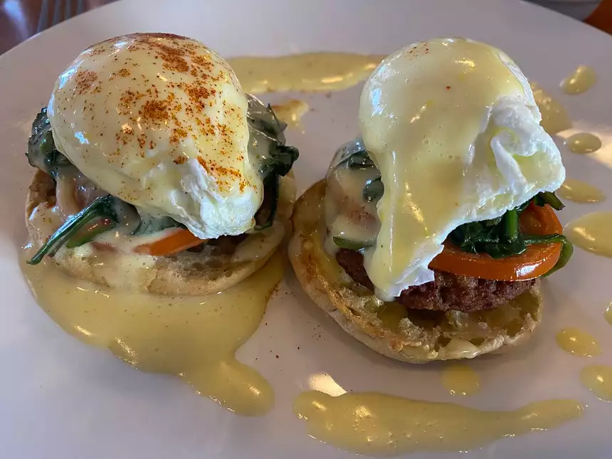 eggs benedict on a white plate with tomatos 