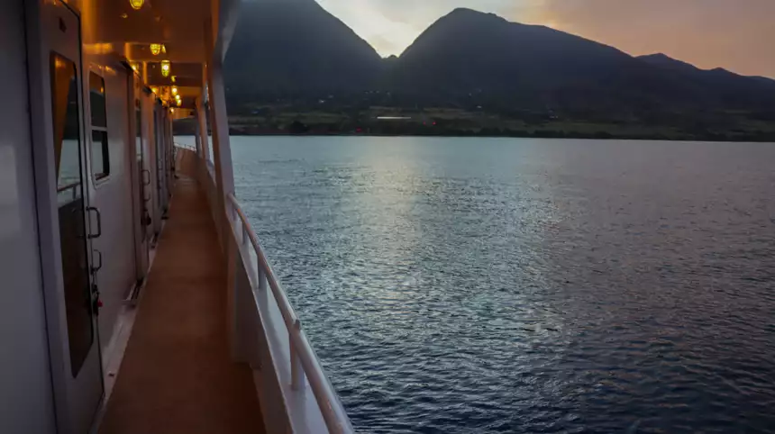 outside of a small cruise ship viewing out to breathtaking mountains and calm water