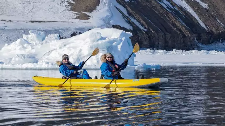 Kayakers in cold weather clothing explore the icy waters of svalbard- iceland-greenland