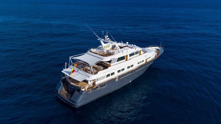 Aerial photo of the blue and white Galapagos Angel yacht sailing over deep blue water