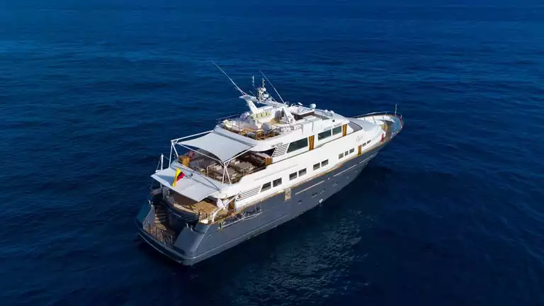 Aerial photo of the blue and white Galapagos Angel yacht sailing over deep blue water